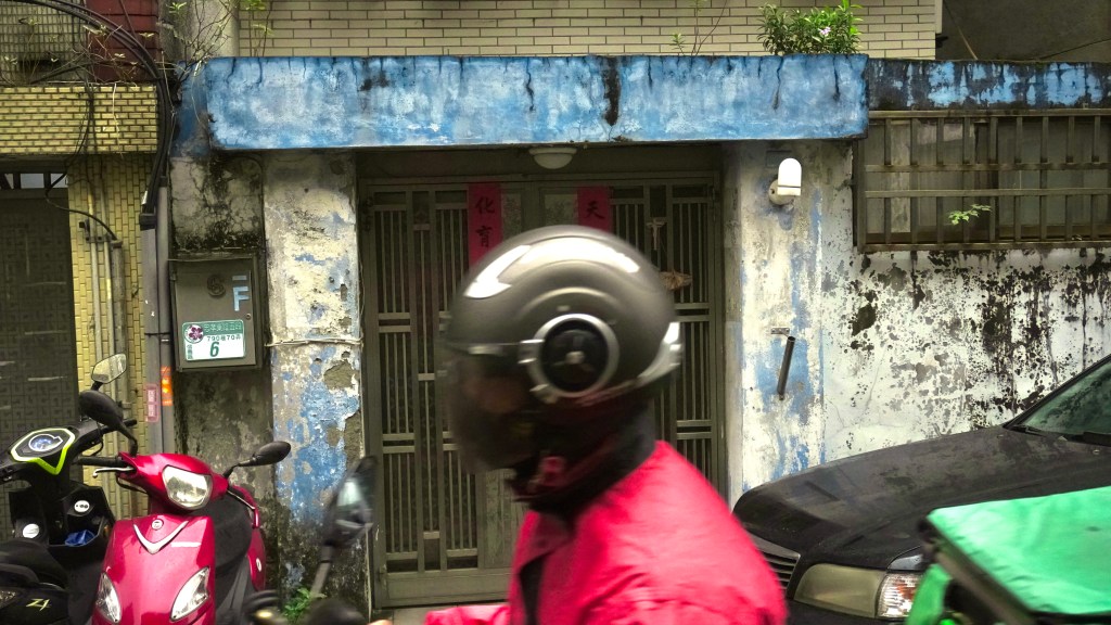 a scooter speeds by a beat up doorway