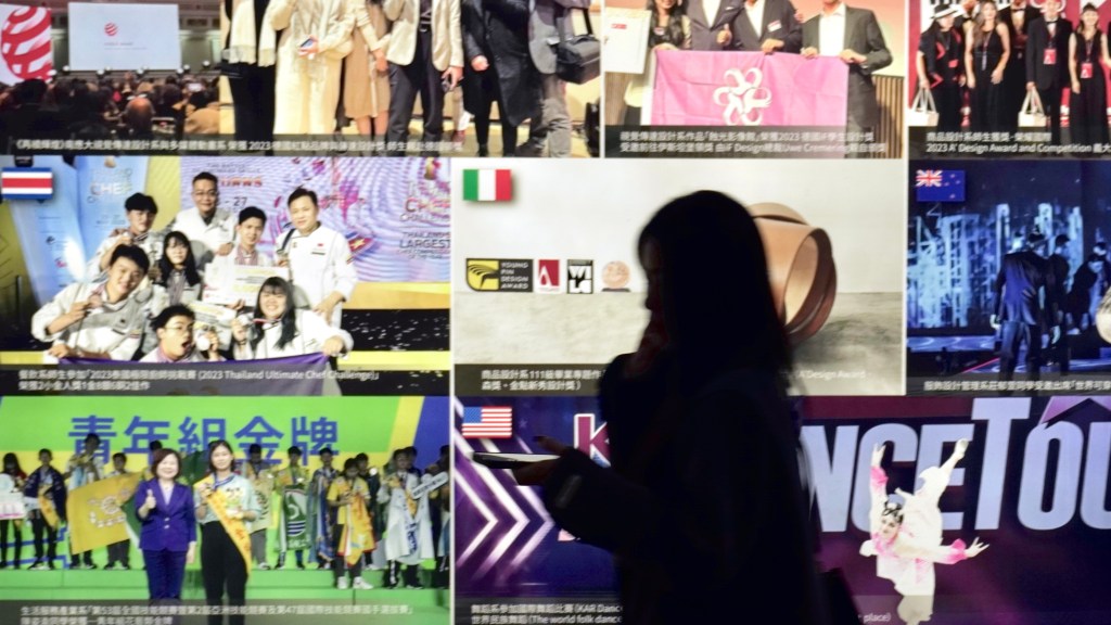 a silhouette of a young woman walking in front of an illuminated advertisement board
